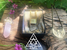 time crystal quartz crystal amulet necklace front view photographed laying between the samadhi rose quartz crystal amulet necklace and the egyptian goddess isis pendant necklace made by chateau de lion cdl-neck-tm-001
